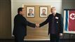 To mænd giver hånd foran billederne af nordkoreanske diktarorer 