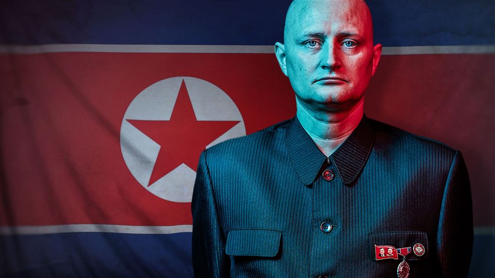 Mand står med sammenbidt udtryk foran det nordkoreanske flag 