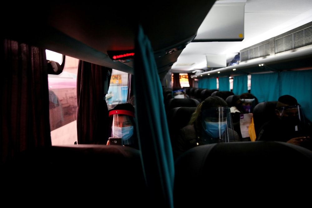 I Peru sidder passagererne i en bus adskilt af gardiner og med hver deres visir og mundbind. 