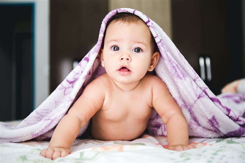 En sød baby med et tæppe over hovedet 