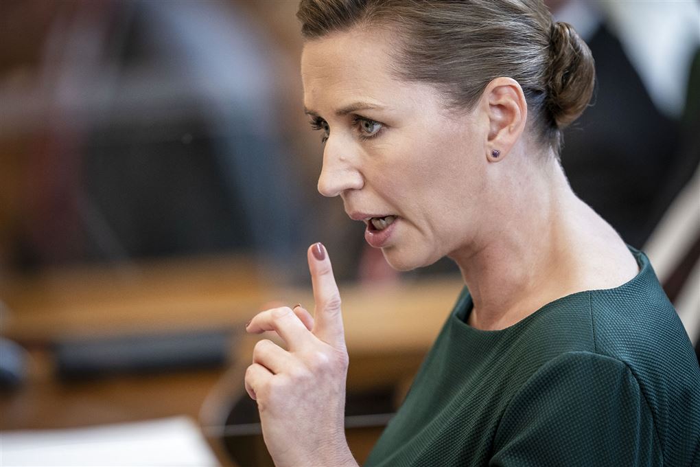 Statsminister Mette Frederiksen med alvorlig mine og en løftet pegefinger hun ses i profil