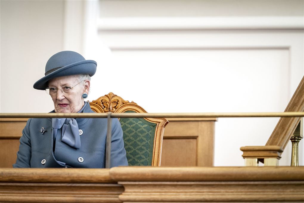 Dronningen til åbningen af folketinget. Hun har alvorlig mine i ansigtet og er klædt i en støvet blå jakke med matchende hat.t