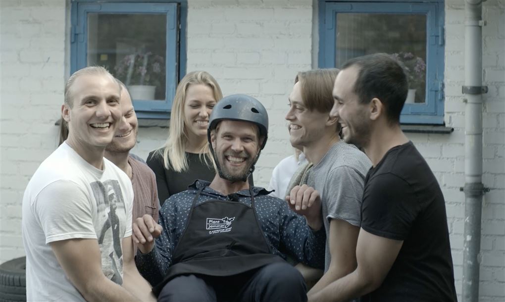 Fem unge folk holder en mand i en guldstol