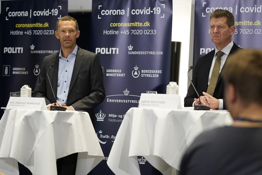 Billede af Erik Brøgger ved onsdagens pressemøde. Han står ved et højt cafébord med en hviddug. Ved et andet bord ved siden af ses Søren Brostrøm
