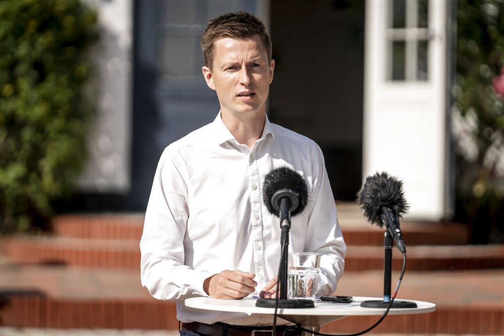 Politikeren Jesper Andersen iført hvid skjorte står ved en udendørs talerstol med to mikrofoner med vindhætter på.