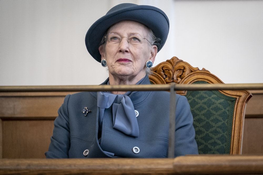 Dronningen til åbningen af folketinget. Hun har alvorlig mine i ansigtet og er klædt i en støvet blå jakke med matchende hat.t