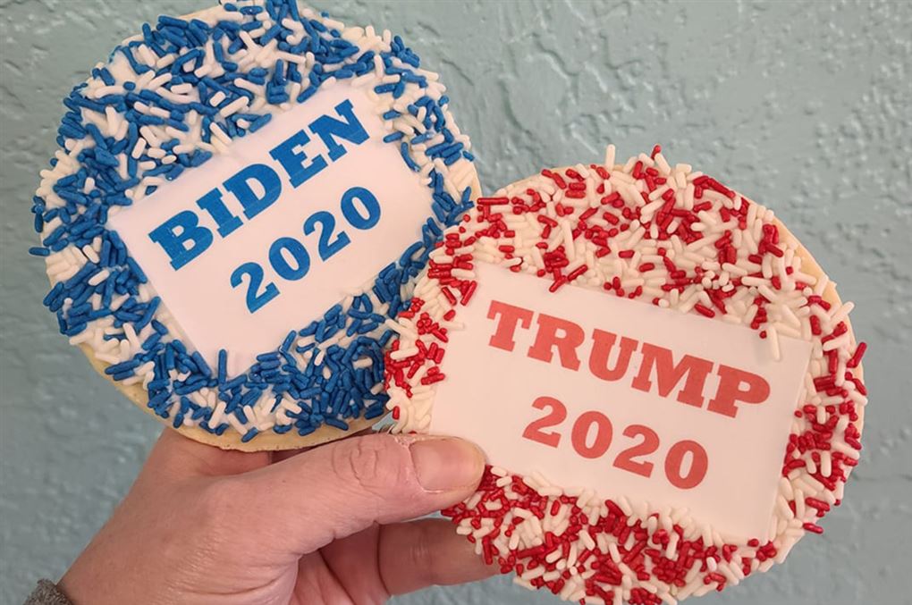 hånd med to kager - en blå og en rød med påskriften Biden 2020 og Trump 2020