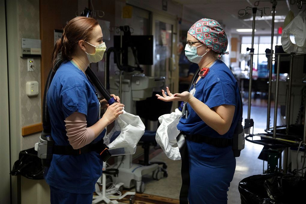 To sygeplejersker med mundbind taler sammen på en hospitalsgang