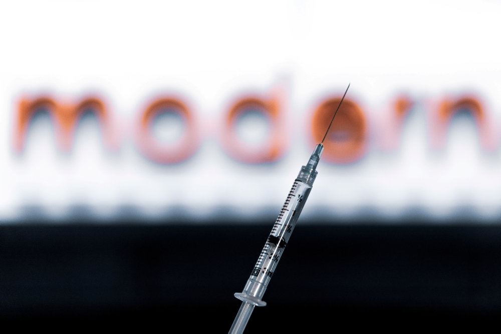 en vaccinenål foran et logo merd Moderna