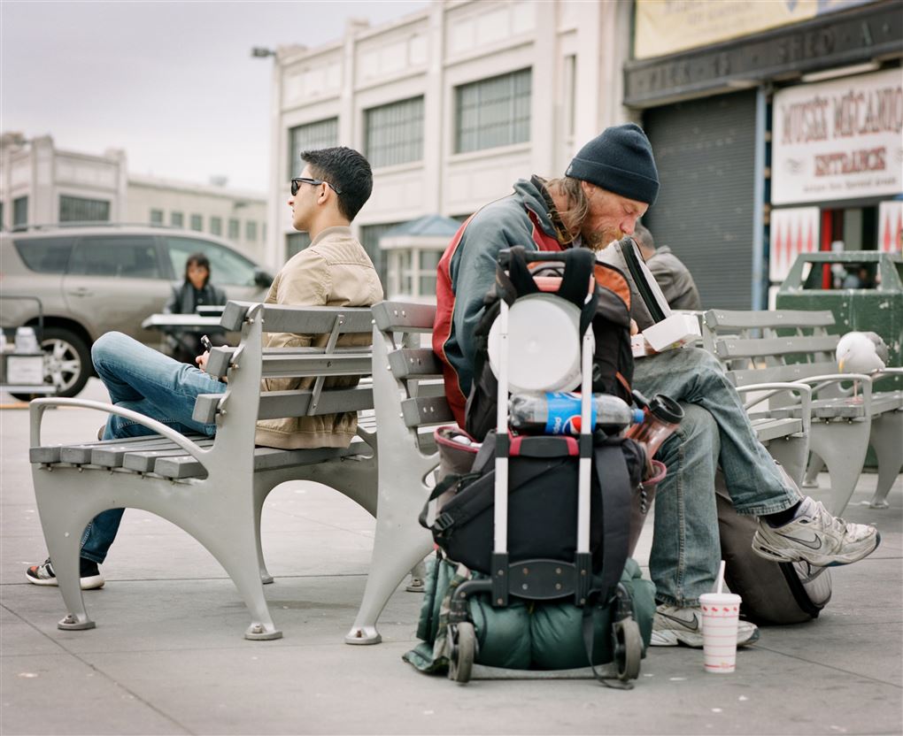 En hjemløs p en bæk ved siden af en ung fyr, som ikke er hjemløs