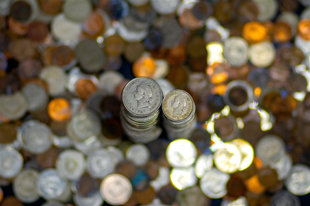 En masse småpenge ligger på et bord. Pengene ses fra oven. Der er også to sirligt stablede tårne af mønter. 