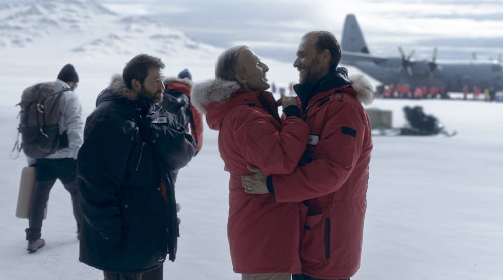 to personer i røde jakker omfavner hinanden på Sydpolen