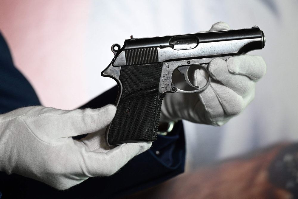 En lille pistol holdt af en mand med hvide handsker