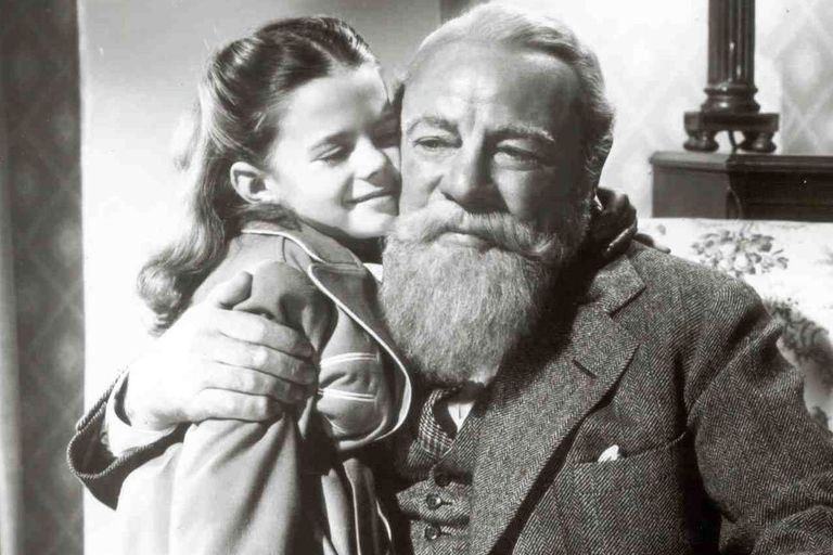 en lille pige krammer en ældre mand med fuldskæg