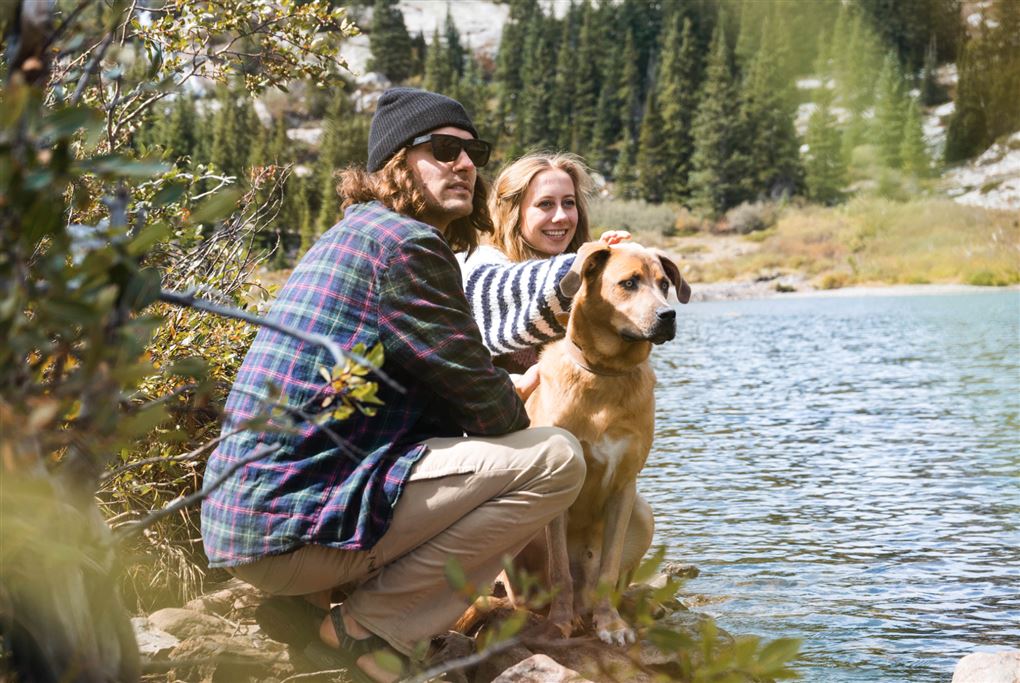 Et par med en hund sidder ved en sø