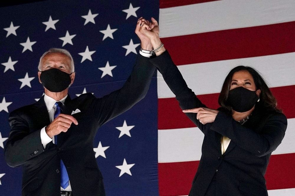 Joe Biden og Kamela Harris står med mundbind og armen i vejret