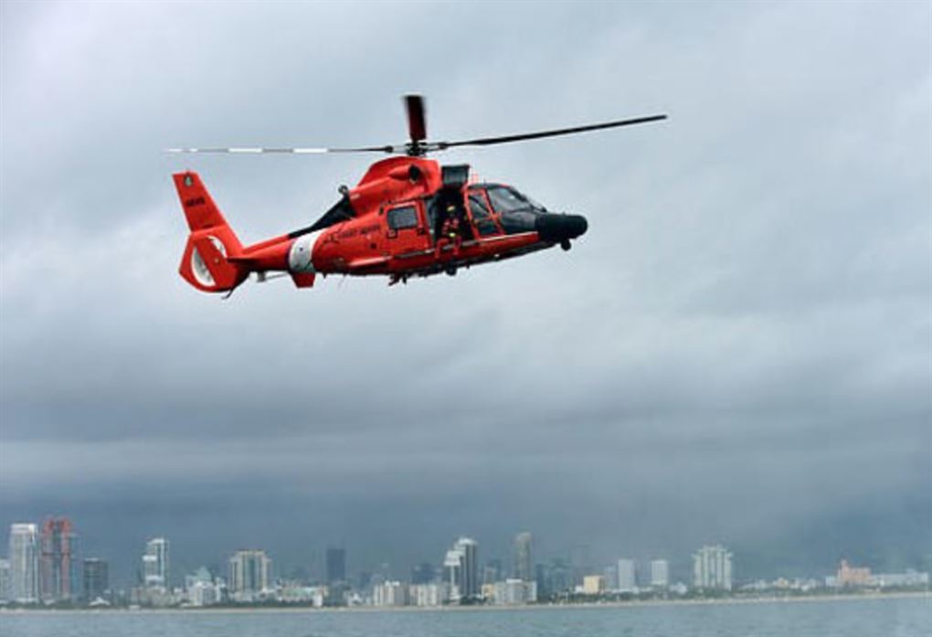 En orange helikopter svæver over vandet