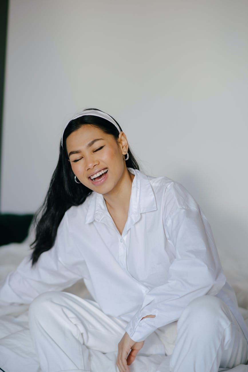 Smilende asiatisk pige i afslappet hvid skjorte