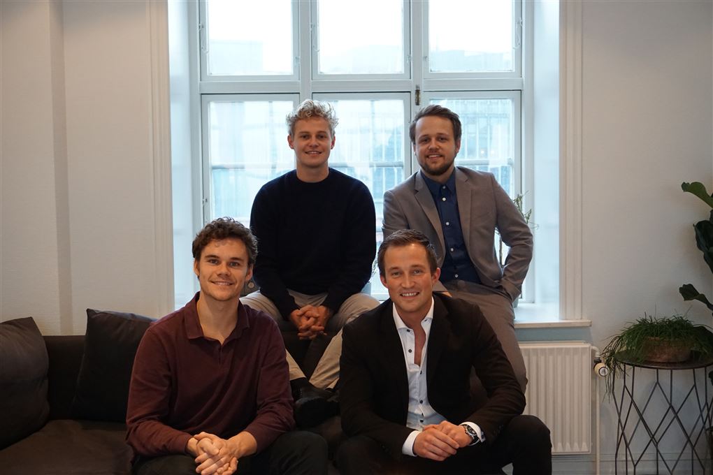 Fire yngre smilende mænd i et kontor
