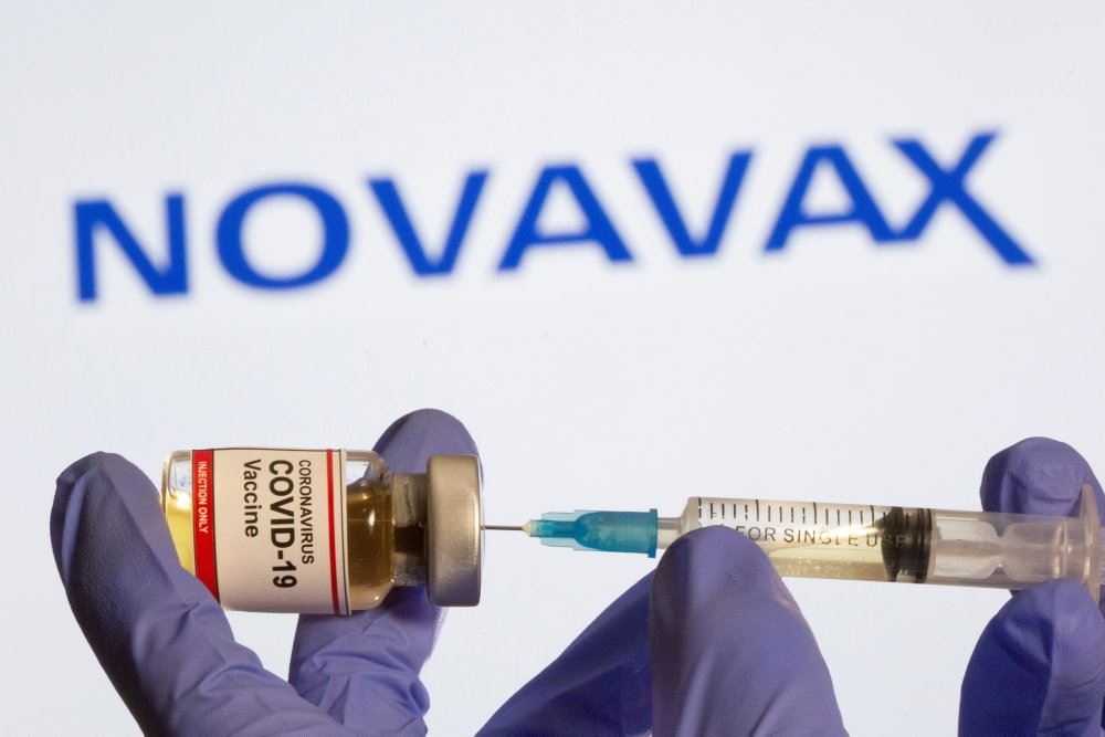kanyle og glas med vaccine med firmanavet Novavax i baggrunden