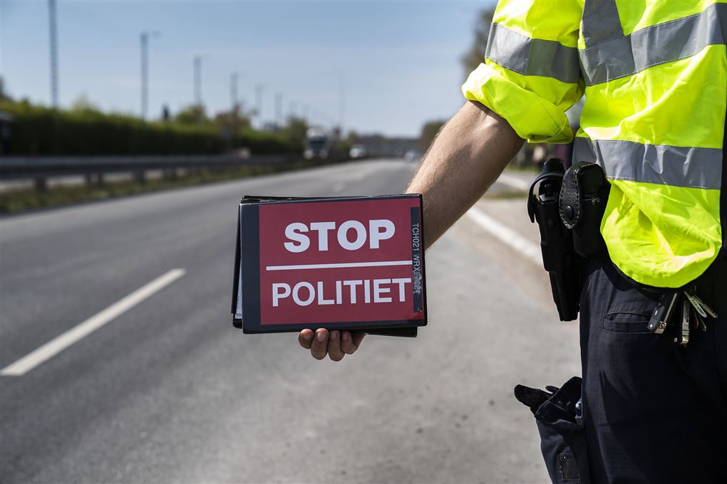 politimand med skilt med påskriften "Stop - politiet" 