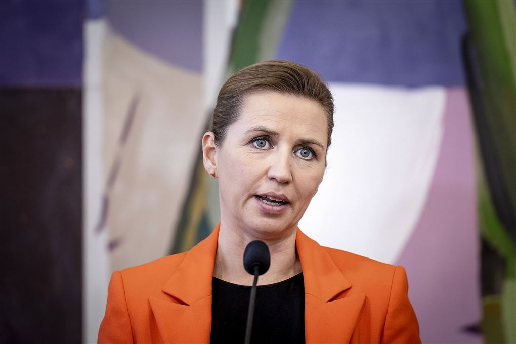 Mette F i en orange jakke