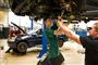 To unge reparerer en bil i en hal