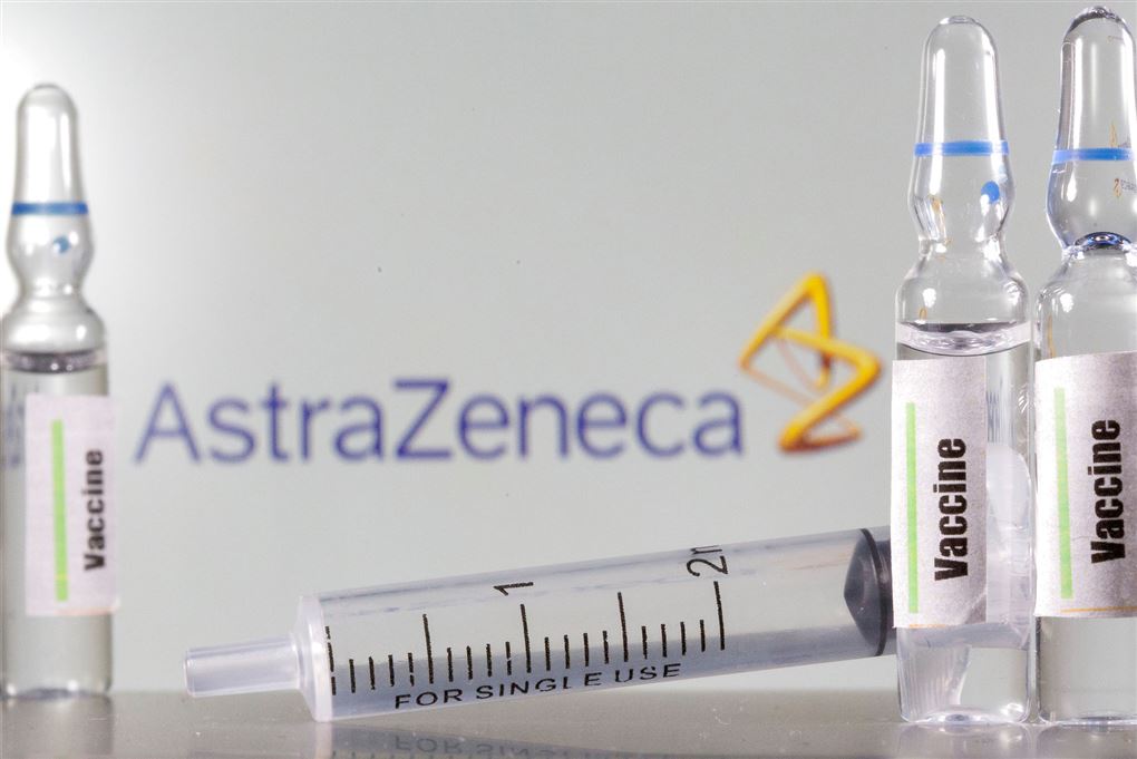 glas og injektionssprøjte ligger på bord foran logo fra astrazeneca