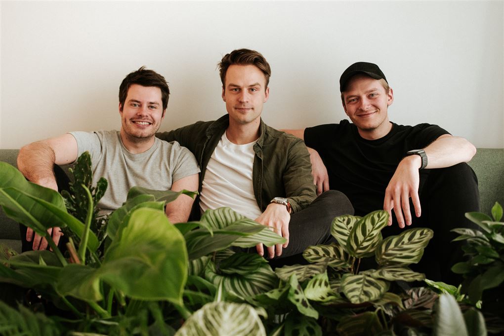 Tre unge mænd i en sofa med planter foran dem