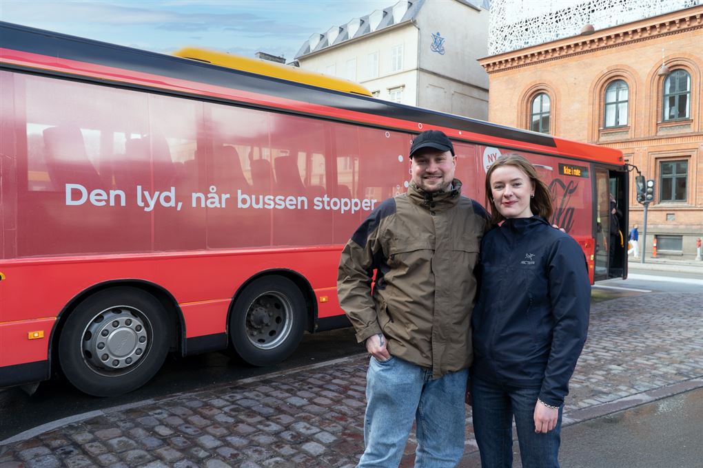 To unge mennesker ved en rød bus