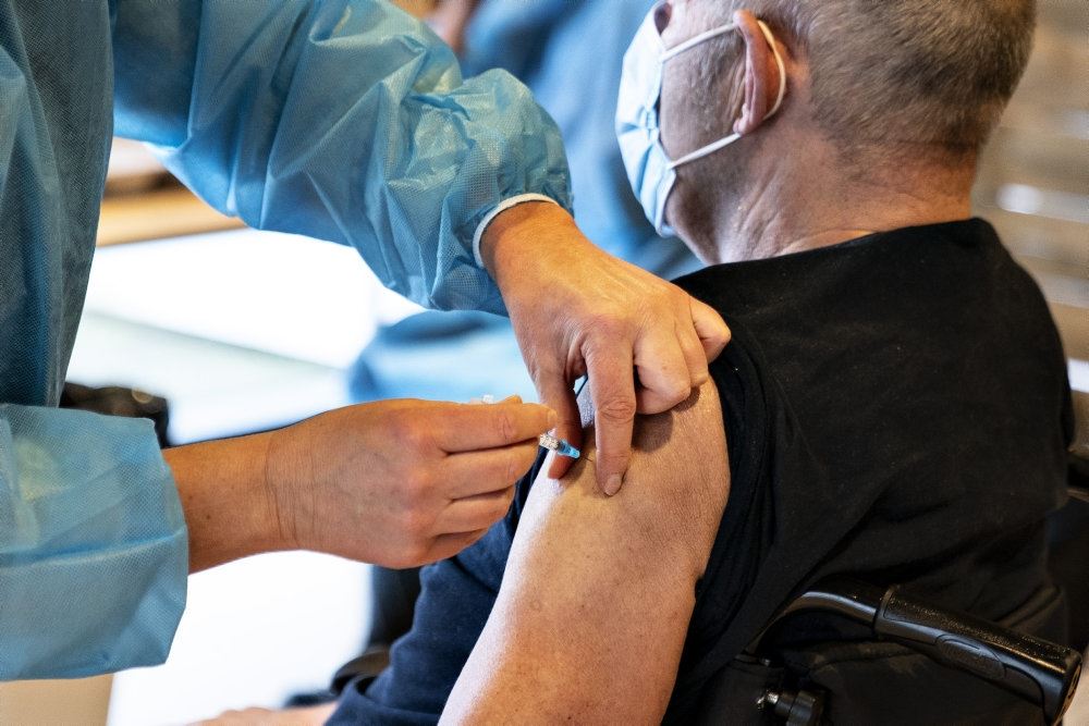 mand får vaccination med et stik i skulderen