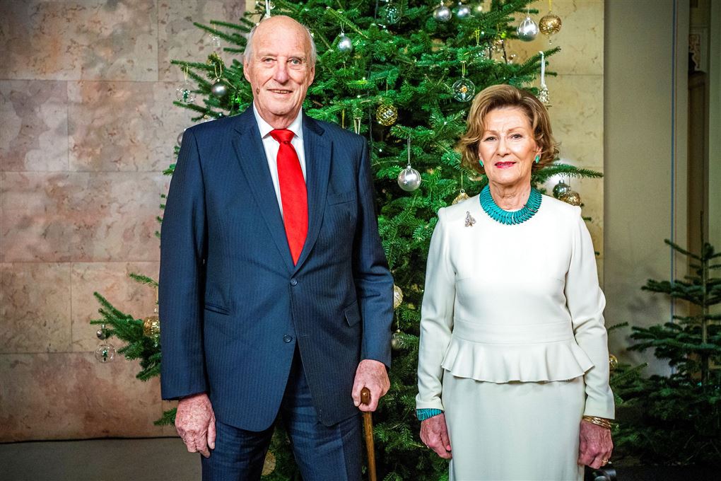 Kong Harald og Dronning Sonja står foran juletræ