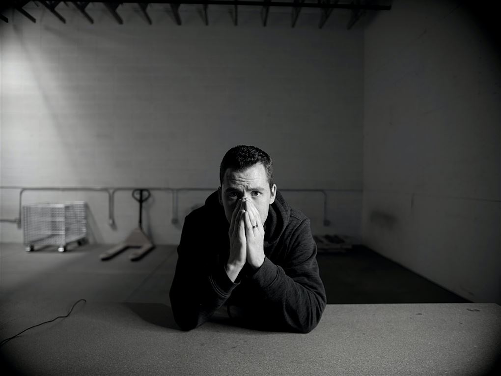En mand sidder fortvivlet med hænderne op for munden i et tomt værksted