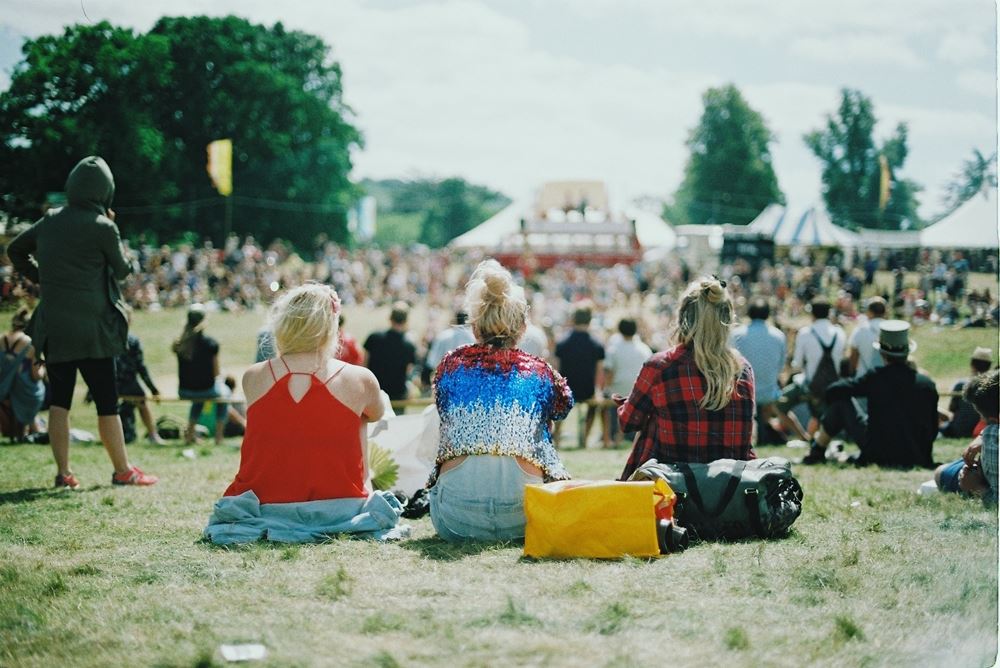 folk sidder på græsset til festival