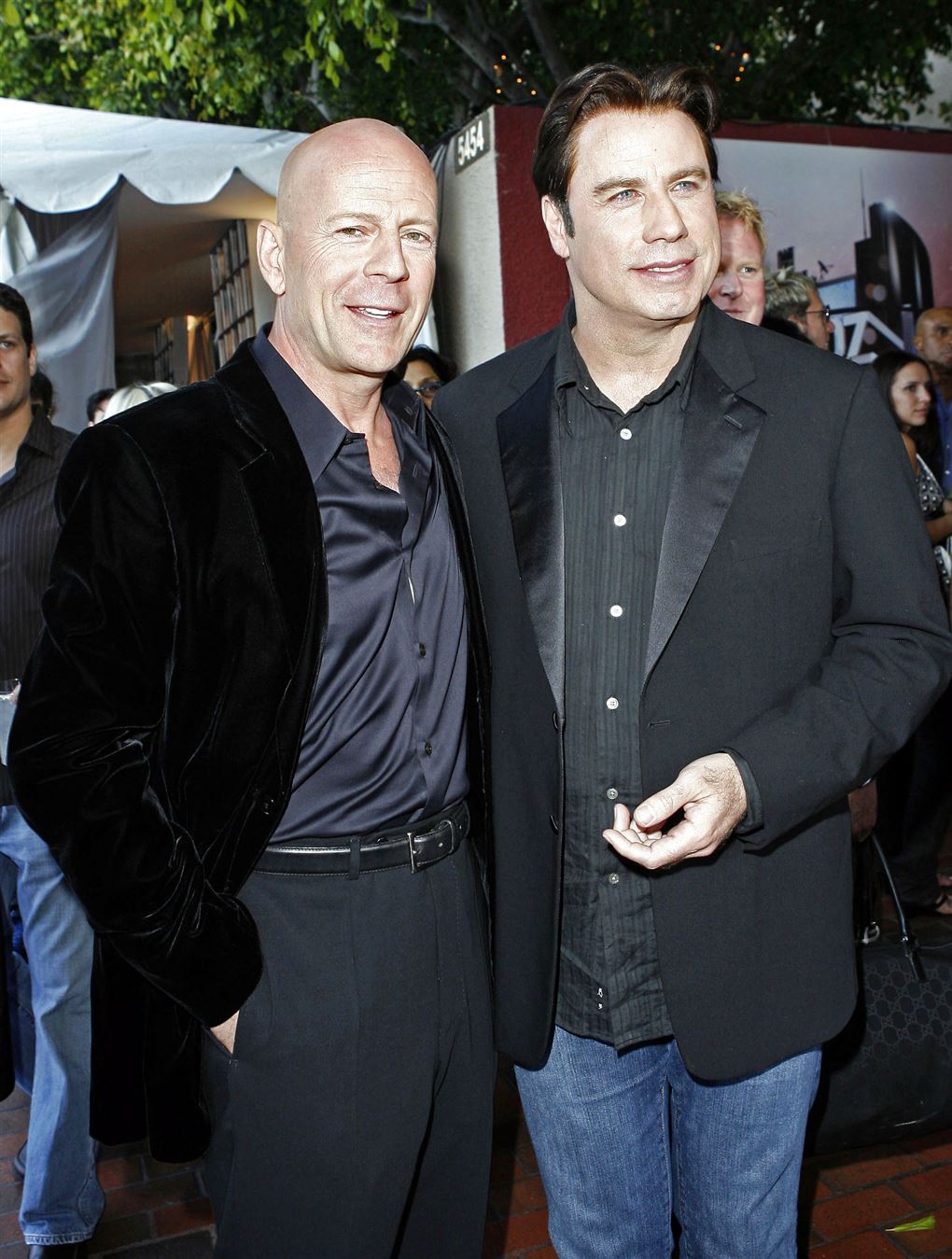 Bruce Willis og John Travolta i jakker og mørke bukser