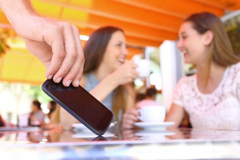 person tager mobiltelefon fra bord