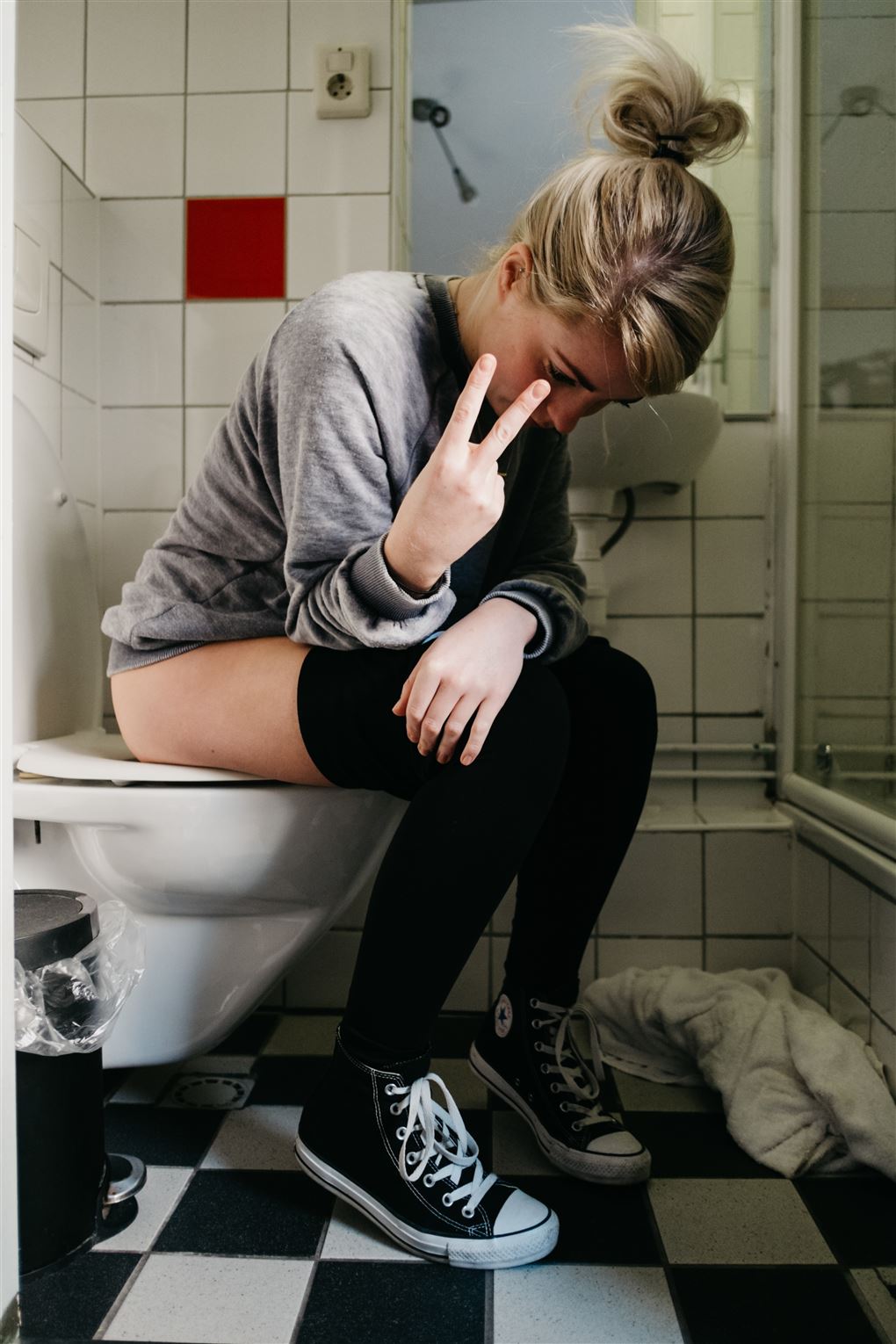 En ung kvinde sidder på toilettet