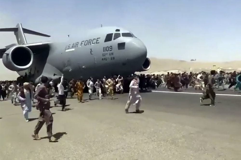 folk løber efter et militærfly i en lufthavn