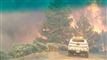 bil holder foran brændende skovområde