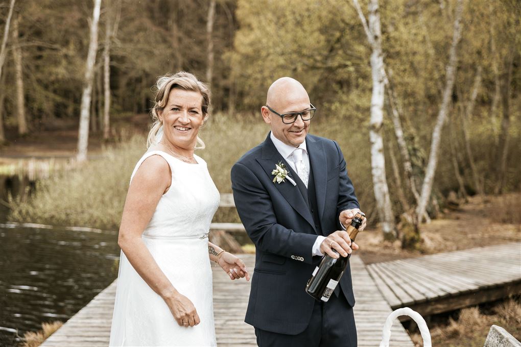 Et brudepar på en bro med champagne