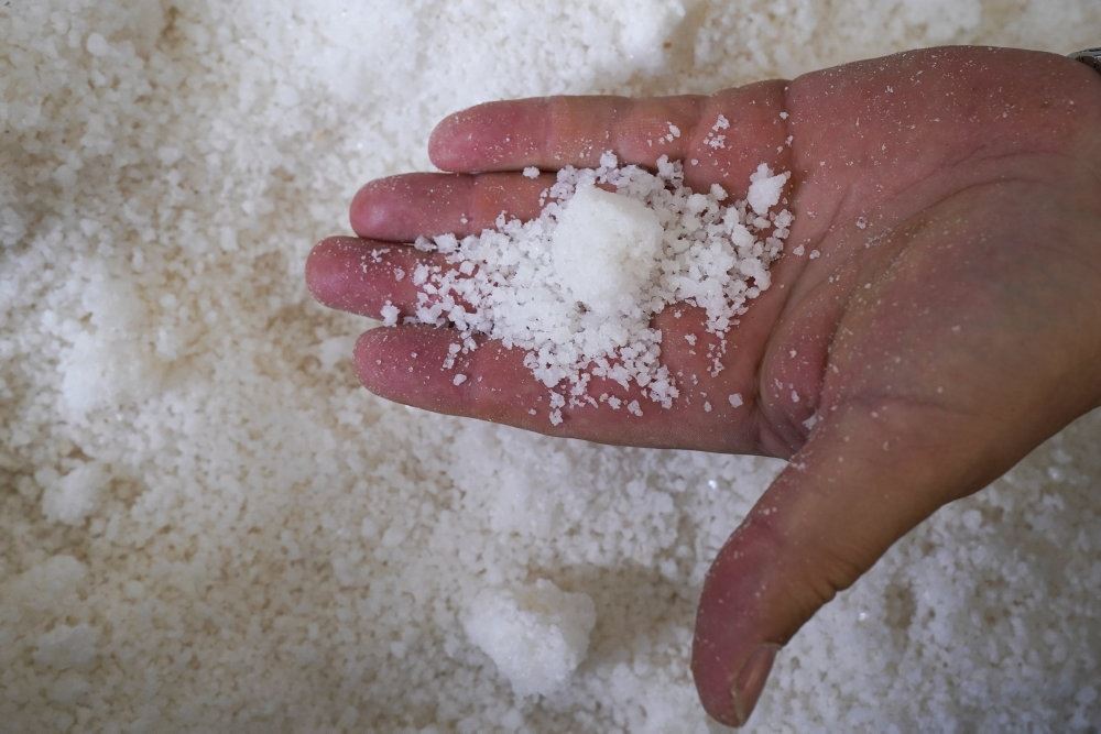 En håndfuld salt taget op fra et stort kar med salt
