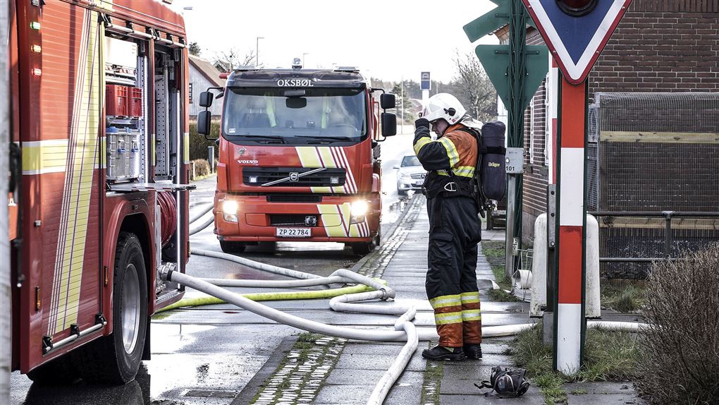 En brandmand ved to brandbiler på en gade
