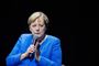 Angela Merkel med en skrigende blå jakke og et alvorligt blik