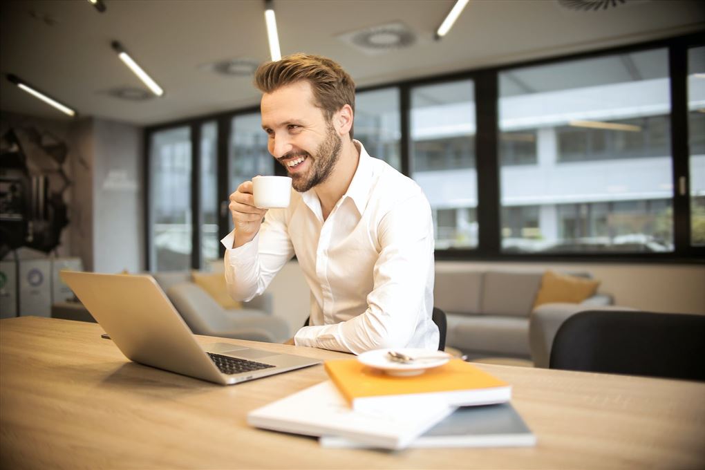 en glad mand drikker kaffe på et kontor