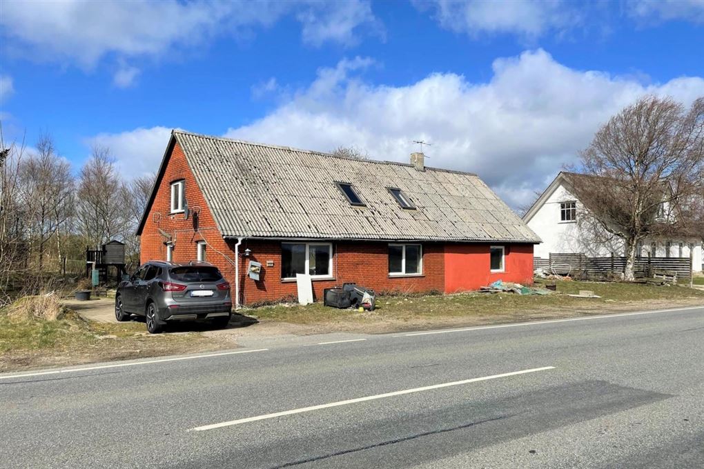 Et faldefærdigt rødstenshus med slidt tag.
