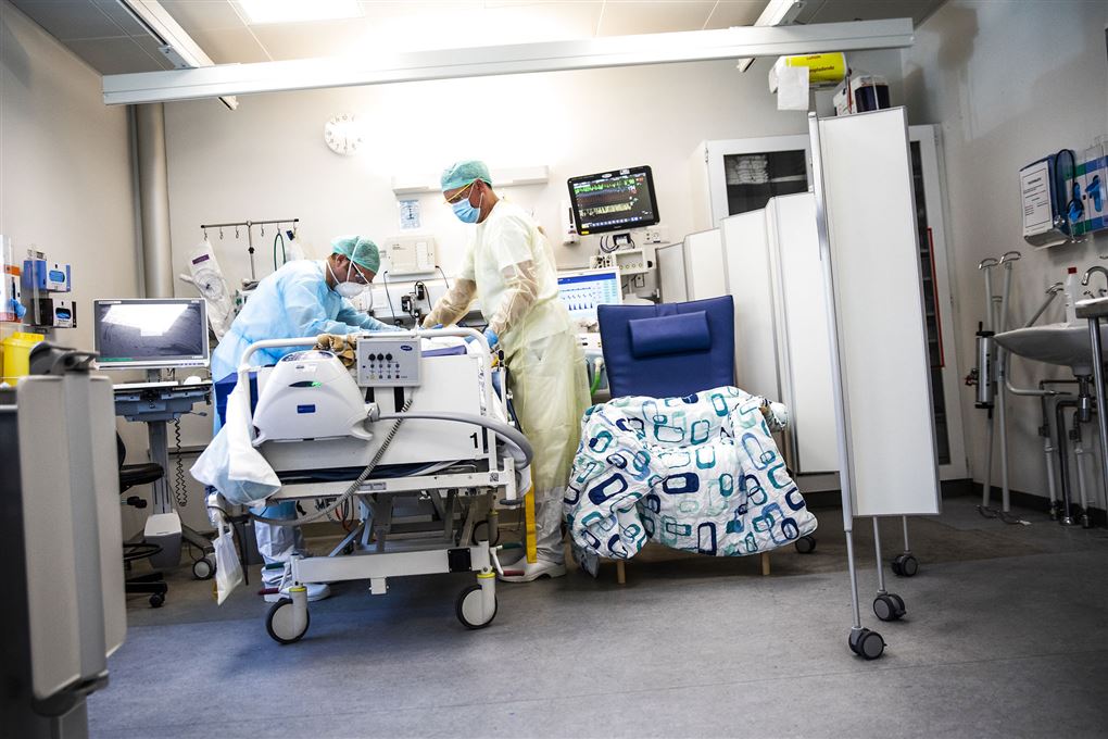 to hospitalsansatte står ved seng med patient