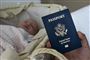 Et mørkeblåt pas foran en lille baby der ligger i en lift 