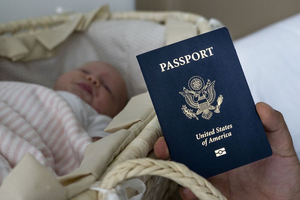 Et mørkeblåt pas foran en lille baby der ligger i en lift 