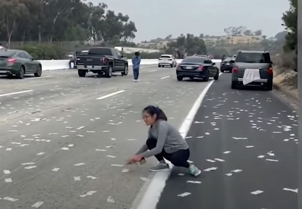 kvinde sidder på vejen og samler penge op
