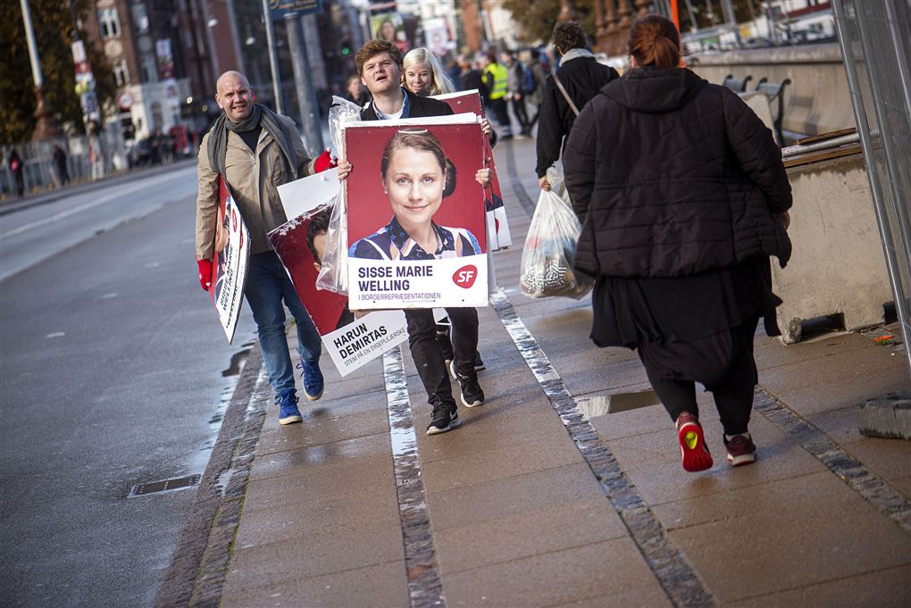 folk går på gaden med valgplakater 